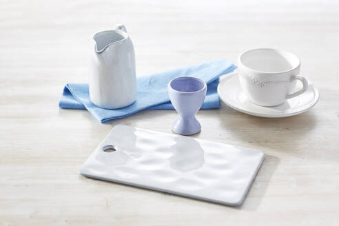 Studio shot of empty milk jug, cup, cutting board, napkin and eggcup - KSWF02361