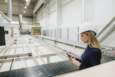 Geschäftsfrau mit Smartphone in der Produktionshalle einer Fabrik - JOSEF18674