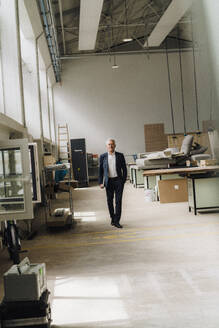 Älterer Geschäftsmann, der in einer Fabrik auf dem Produktionsboden geht - JOSEF18819