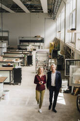 Geschäftsfrau und Geschäftsmann gehen in einer Fabrik auf dem Produktionsboden - JOSEF18836