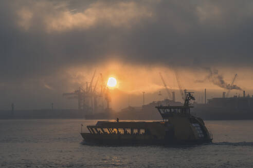 Germany, Hamburg, Sun rising over harbor ferry - KEBF02704