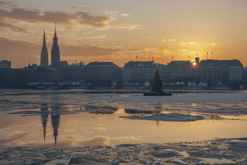 Deutschland, Hamburg, Eisschwimmen auf der Alster bei Sonnenuntergang mit der Skyline der Stadt im Hintergrund - KEBF02714