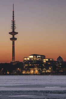 Germany, Hamburg, Ice floating in Alster Lake at dusk with Heinrich-Hertz-Tower in background - KEBF02720