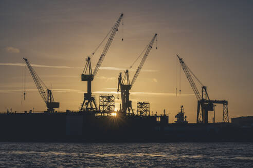 Deutschland, Hamburg, Kräne des Hamburger Hafens bei Sonnenaufgang - KEBF02724