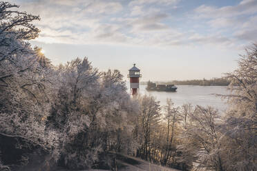 Deutschland, Hamburg, Vereiste Bäume vor dem Leuchtturm Wittenbergen im Winter - KEBF02745