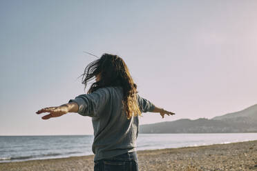 Woman standing with arms outstretched at beach - ANNF00137