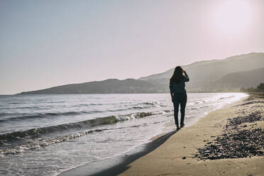 Frau geht in der Nähe des Ufers am Strand spazieren - ANNF00141