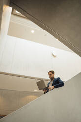 Geschäftsmann mit Laptop auf einer Treppe - JOSEF18880