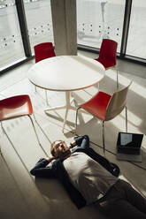 Geschäftsmann auf dem Boden liegend mit Laptop und Stühlen im Büro - JOSEF18882