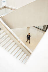 Businessman standing in corridor seen from staircase - JOSEF18920