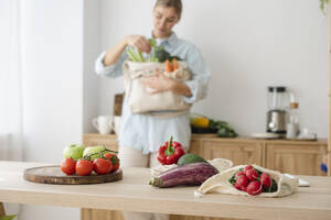 Vielfalt an frischem Bio-Gemüse in wiederverwendbaren Tüten auf dem Tisch bei einer Frau zu Hause - ALKF00264