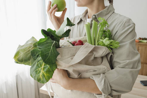 Woman holding reusable bag full of organic vegetables and fruits - ALKF00271
