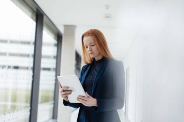 Redhead businesswoman using tablet PC at office - JOSEF18955