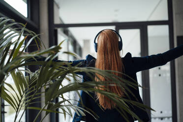 Redhead businesswoman enjoying listening to music at office - JOSEF18958