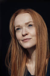 Thoughtful redhead woman against black background - JOSEF19018