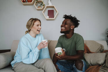 Fröhliches Paar genießt Kaffee auf dem Sofa zu Hause - MDOF01075