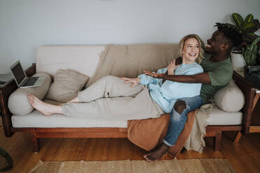 Glückliches Paar genießt einen Film auf dem Sofa zu Hause - MDOF01079