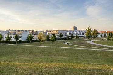 Germany, Bavaria, Augsburg, Grassy area in front of new modern suburban flats at dusk - MAMF02849