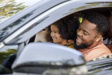 Ein lächelnder Mann genießt einen Ausflug mit seiner Tochter im Auto - IKF00361