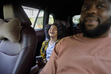 Happy girl sitting in back seat of car - IKF00366