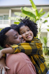 Smiling man embracing daughter with curly hair - IKF00376