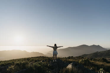 Woman with arms outstretched standing on mountain under sky - LHPF01582