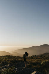 Woman with arms outstretched standing on mountain under sky - LHPF01584