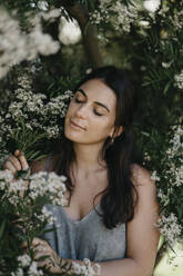 Woman with eyes closed amidst flowers - LHPF01586