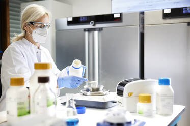 Scientist measuring chemical on weighing scale in laboratory - CVF02378