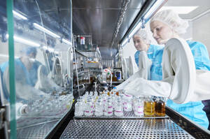 Wissenschaftler arbeiten mit Chemikalienflaschen in einer mikrobiologischen Sicherheitswerkbank - CVF02387
