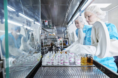 Scientists working with chemical bottles inside microbiological safety cabinet - CVF02387