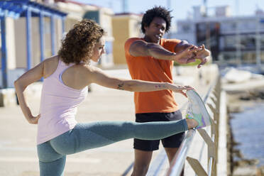 Couple stretching and exercising on pier in coastal area - JSMF02738
