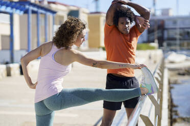 Couple stretching and exercising on pier in coastal area - JSMF02739
