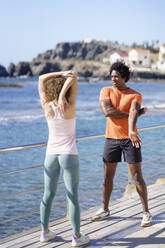 Freund und Freundin machen Dehnungsübungen auf dem Pier in der Küstengegend - JSMF02742