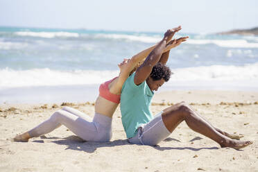 Couple sitting and stretching arms at beach - JSMF02768