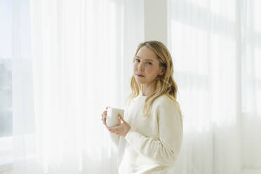 Blonde Frau hält Kaffeetasse durch durchsichtigen Vorhang - SEAF01877