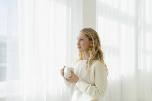 Lächelnde Frau mit Kaffeetasse vor einem durchsichtigen Vorhang - SEAF01878