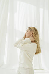 Blond woman standing in front of white curtain - SEAF01922
