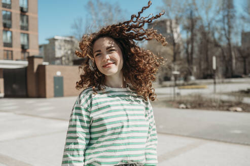 Smiling woman with tousled hair at sunny day - ANAF01343