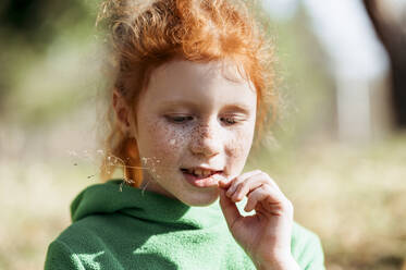 Cute girl with redhead biting sprig on sunny day - ANAF01344