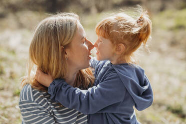 Mother and daughter rubbing noses on sunny day - ANAF01348