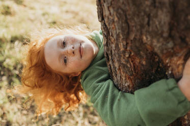 Girl embracing tree trunk in forest - ANAF01364
