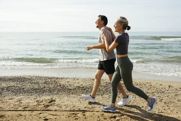 Glückliches Paar beim Laufen und Spaß haben am Strand - EBSF03255