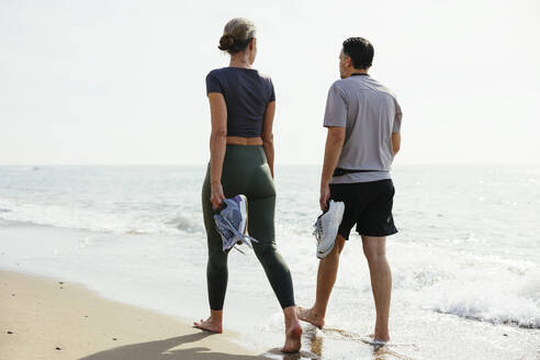 Paar mit Sportschuhen in der Nähe des Ufers am Strand - EBSF03268