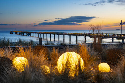 Germany, Mecklenburg-Vorpommern, Binz, Glowing spheres on beach of Rugen island with Seebrucke Binz pier in background - WGF01462