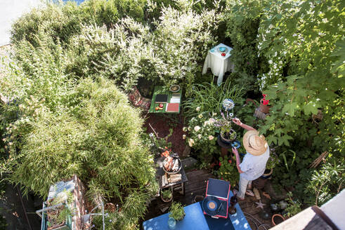 Älterer Mann kocht Essen inmitten von Pflanzen im Garten - HHF05890