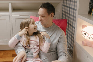 Happy girl sitting with father looking face to face at home - VIVF00770