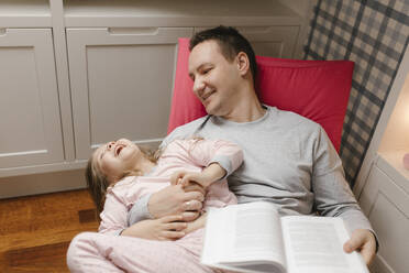 Glückliches Mädchen lachend mit Vater zu Hause sitzend - VIVF00772
