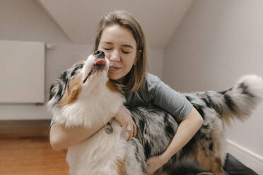 Woman embracing Australian Shepherd at home - VIVF00778