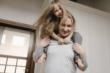 Smiling father carrying daughter on shoulders at home - VIVF00785